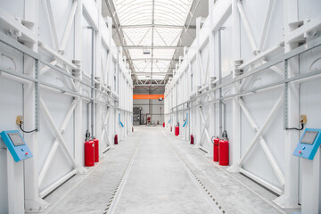 Fototapeta premium Long white warehouse corridor with red fire extinguishers