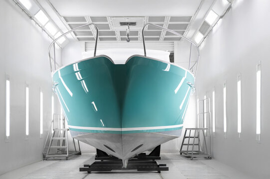 Teal boat rests inside clean, bright paint booth