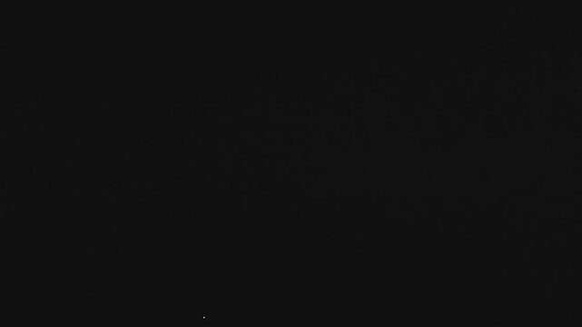 A mesmerizing super slow motion shot captures single water drop creating perfect spherical splash and tiny ripples in black liquid surface under a dark sky at night, elegant and tranquil motion.