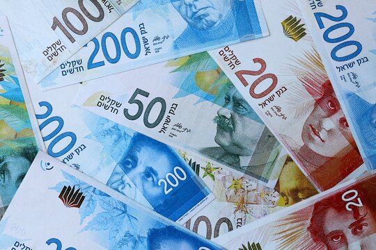 Israeli new shekel money bills in pile on table. Israel ILS currency cash close up