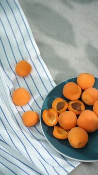apricots in a blue plate on the table in sunlight and shadow from the leaves