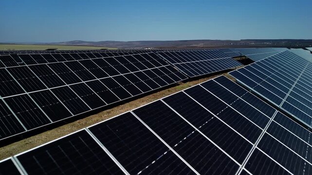 Solar panels arranged in rows on a grassy field under a clear blue sky, showcasing renewable energy technology in a rural landscape