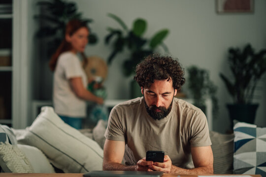 Man ignoring partner, focused on smartphone, showing digital addiction and relationship problems