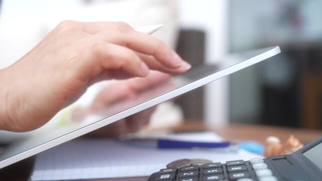 Person using tablet and stylus to manage finances and calculate expenses. Digital accounting, budget planning, tax preparation, savings management and personal finance concept.
