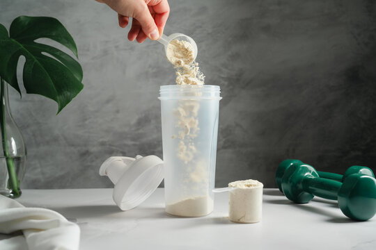 Scoop of protein powder poured into shaker for muscle recovery drink