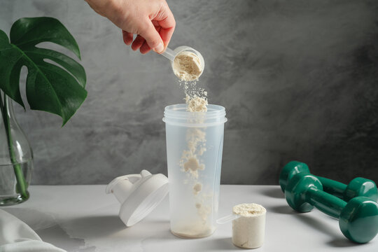 Whey protein powder being added to shaker for healthy lifestyle concept