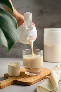 Pouring vanilla protein shake into glass, sports nutrition supplement and healthy lifestyle