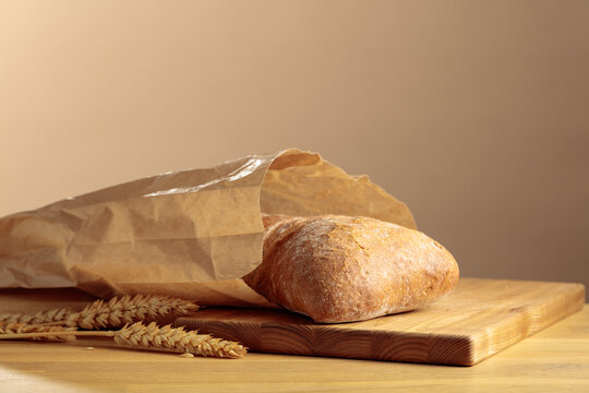 Fresh backed ciabatta bread in paper bag on a wooden table.