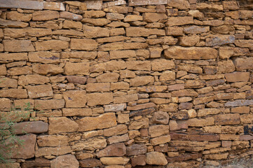 Obraz premium Close-up view of a yellow limestone wall in Jaisalmer, Rajasthan, showcasing natural stone textures, warm golden tones, and the distinctive architectural character of the historic Golden City.