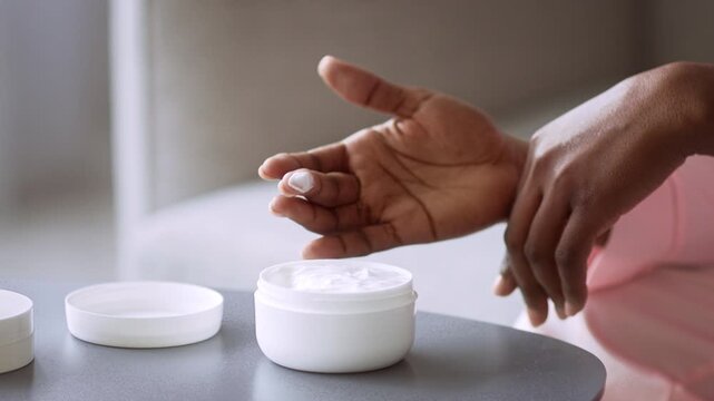 Focused Unrecognizable Black Female Applying Moisturizing Skin Cream With Finger At Home, Enjoying Daily Skincare Routine At Cozy Indoor Setting. Emphasizing Self-care And Wellness Concept.