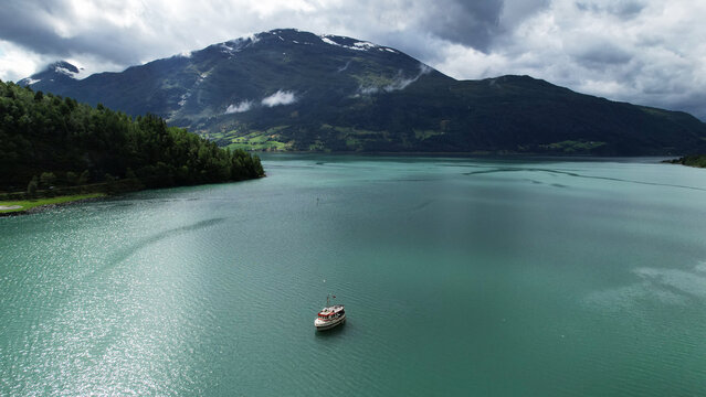 Tour Boat on Lovatnet Lake Beneath Dramatic Mountains in Loen, Norway