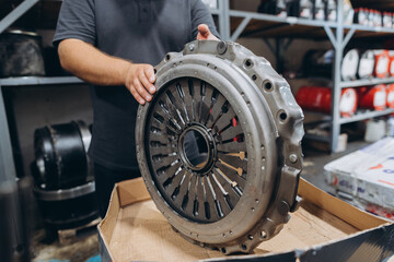 Fototapeta premium Mechanic holding car clutch in auto repair shop
