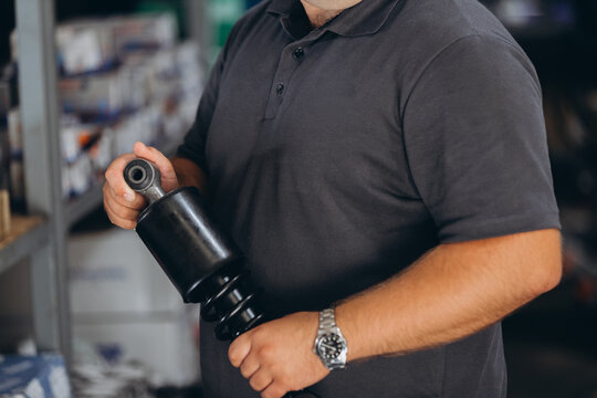 Mechanic holding car shock absorber in workshop