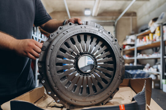 Mechanic holding new clutch pressure plate in auto workshop