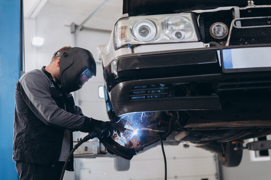 Mechanic welding car frame in auto repair shop