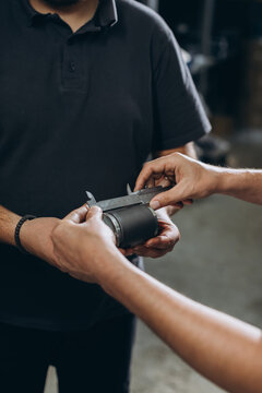 Mechanics measuring car part in workshop
