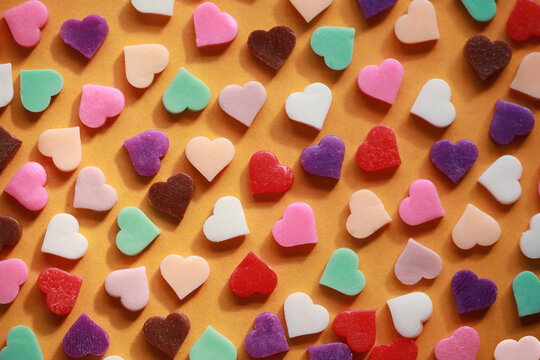 Colorful heart-shaped chocolates flat lay background