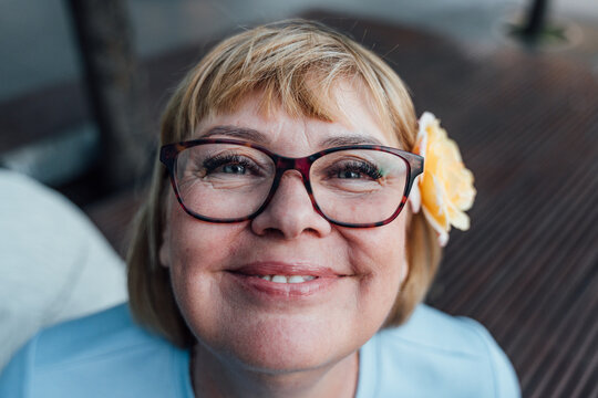 Cheerful Senior Woman With Rose In Hair Smiling Directly At Camera Close Up Portrait