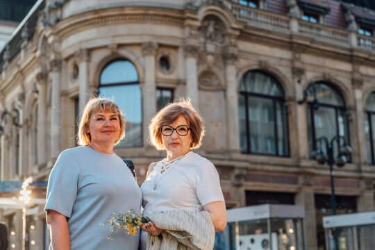 Elegant Senior Women Posing Together Near Historic Architecture In European City Center
