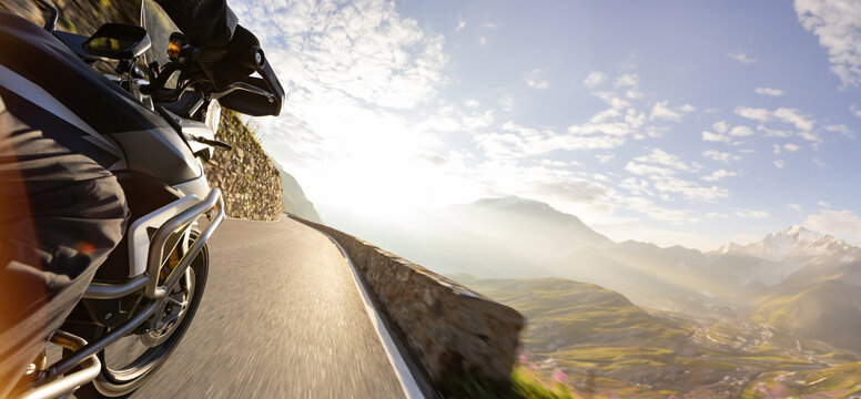 Motorcycle rider riding in Italian Alps during sunrise
