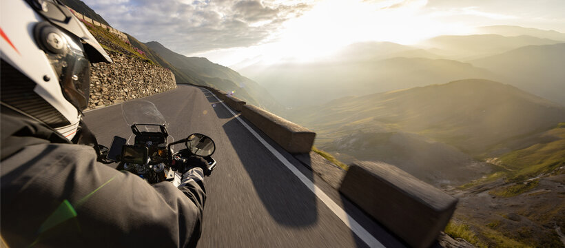Motorcycle rider riding in Italian Alps during sunrise