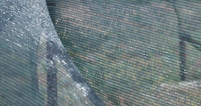 Protective shade netting waving in the wind at a construction site