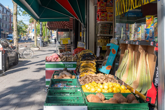 Produce display outside Amsterdam neighborhood toko on sunny urban sidewalk with tropical groceries