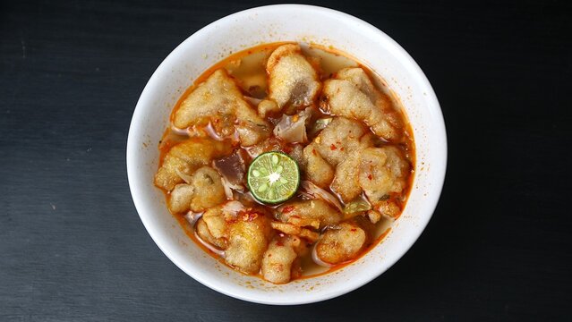 Baso Aci, Traditional Indonesian Spicy Meatball Soup with Lime in a White Bowl on Black Background