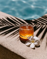 Obraz premium A jar of golden gel with a white flower by a swimming pool