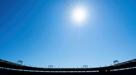 Fototapeta premium Bright sun in blue sky over stadium roof silhouette. Summer sports background with copy space