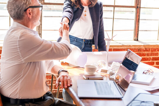 Two professionals shaking hands in a bright office setting.