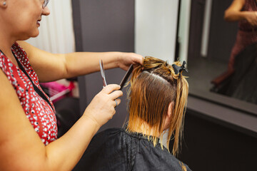 Fototapeta premium Hair stylist giving bob asymmetrical haircut to young woman