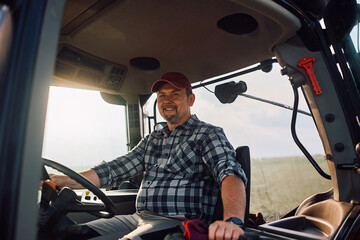 Happy agricultural worker in tractor looking at camera. © Drazen