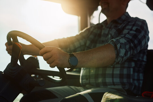 Close up of agricultural field worker driving tractor at sunset.