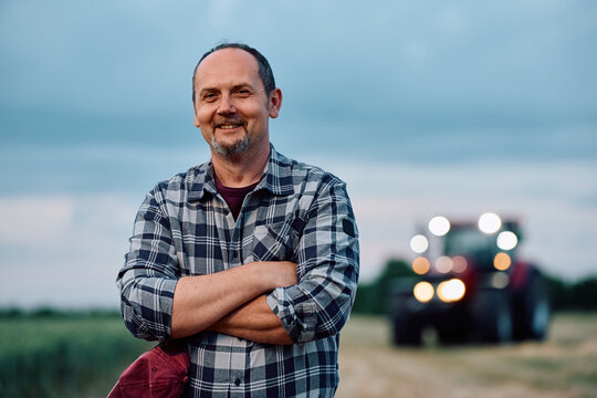 Successful farm owner standing in field and looking at camera.