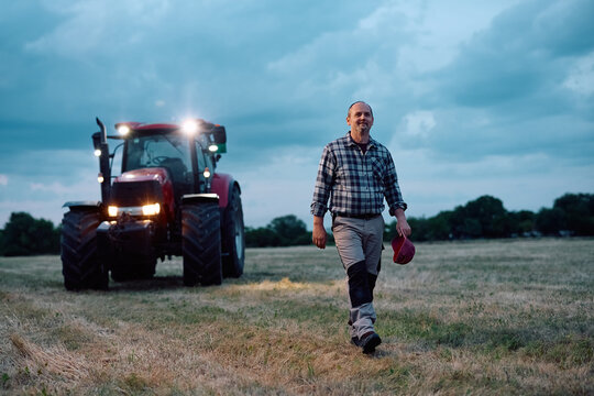 Happy mature agricultural worker walking in field.