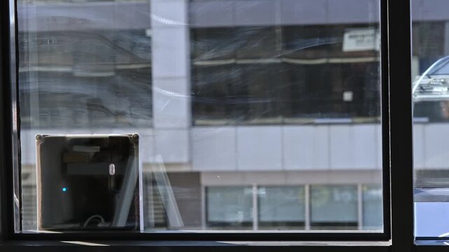 Robotic window cleaner attached to modern office glass, washing an urban building facade with city reflections, representing automation, hygiene, smart technology, and maintenance.