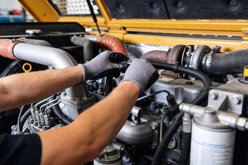 Obraz premium Mechanic wearing gloves works on heavy machinery engine, focusing on turbocharger and fuel system