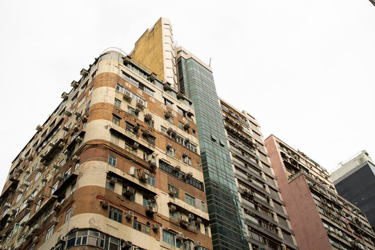 Urban residential building with air conditioners and windows under overcast sky in city