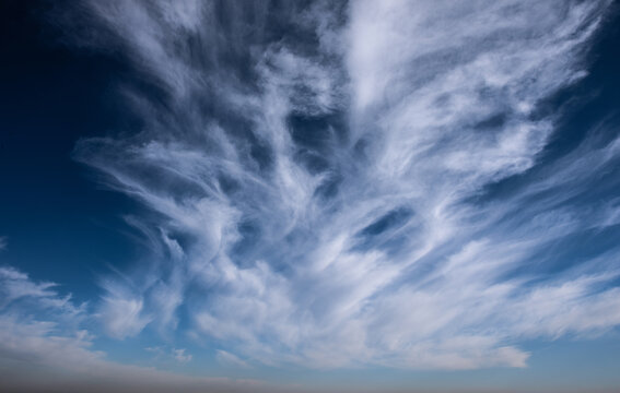 Bright blue sky with large white cumulus clouds and soft cirrus streaks, illuminated by natural daylight. nature, climate, environment, freedom, and relaxation.