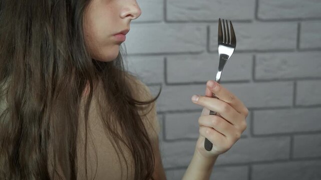 Hungry teenager. Surprised young girl looks at an empty fork