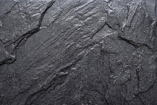 Dark grey slate stone surface with wet texture and water droplets