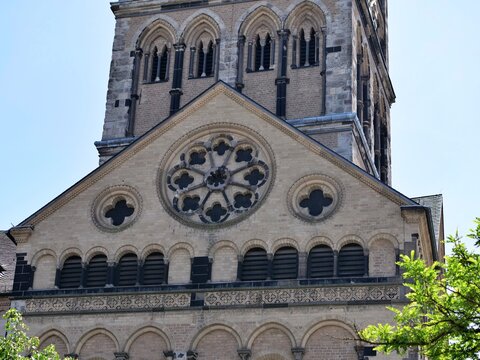  architectural 
shot showcasing the ornate stone 
facade of a historic Romanesque 
church or cathedral. The composition 
highlights a beautifully carved stone 
rose window in the center, surrounded 
b