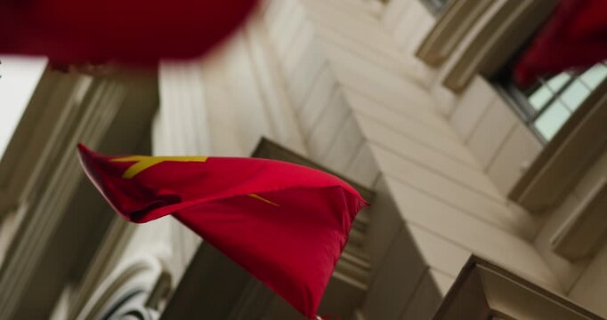 Majestic Vietnamese flag, a vibrant red with a golden star, proudly waves in the wind against the backdrop of a grand, classic building, symbolizing national pride and the enduring spirit of Vietnam.