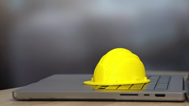 Yellow hard hat on a laptop. Architecture planning and construction management. Engineering in building projects, infrastructure development and professional design