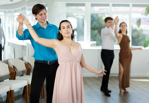 Energy young man paired girl and dancing samba in couple during lesson. Leisure activity. Two couples practice and hone their skills in performing slow dance program, classic slow dance style