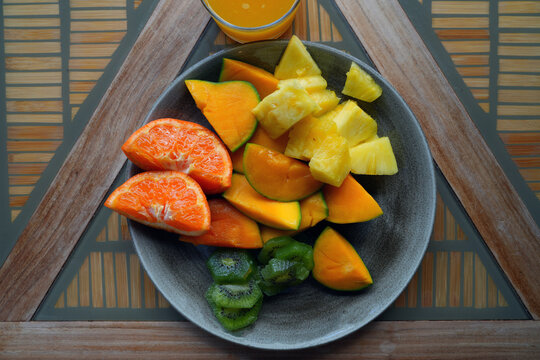 View of a healthy tropical fruit platter with pineapple, clementine, kiwi, and mango