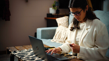 Young woman shopping online with her credit card at home after returning from work. E-commerce,...