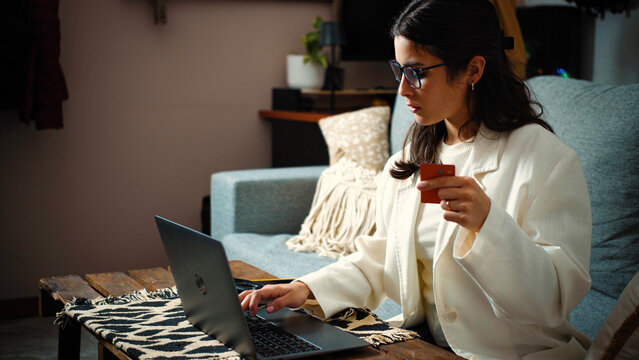 Young Hispanic woman frustrated after her credit card payment is declined while shopping online with her laptop. Financial difficulties and personal finance concept.
