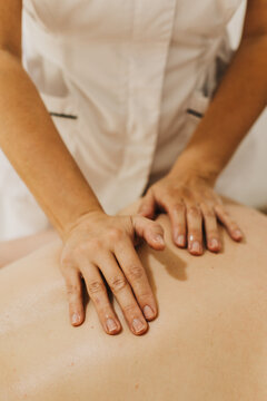 Close up of back massage therapy session. Female massage therapist's hands.